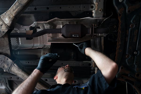 Mechanic AJ Flores applies a marking sticker to a catalytic converter, part of a pilot program by the Minnesota Department of Commerce to prevent cata