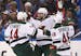 The Minnesota Wild's Jason Zucker, middle, reacts after scoring against the St. Louis Blues in the first period during the first round of the NHL play