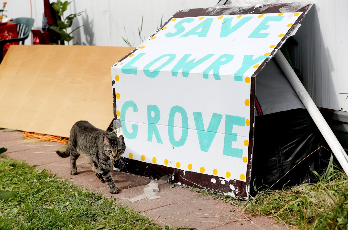 A cat belonging to Lowry Grove mobile home park resident Bill McConnell walks by a sign outside McConnell's home Thursday, June 29, 2017, in St. Anthony, MN. "This is where I was going to retire," McConnell said. Lowry Grove closed it's gate and all residents had to be gone by 12 midnight on July 1, the space slated to be redeveloped into multiple-family housing.] DAVID JOLES &#xef; david.joles@startribune.com It&#xed;s the tale of two parks, with Lowry Grove in St. Anthony and Park Plaza in Fri