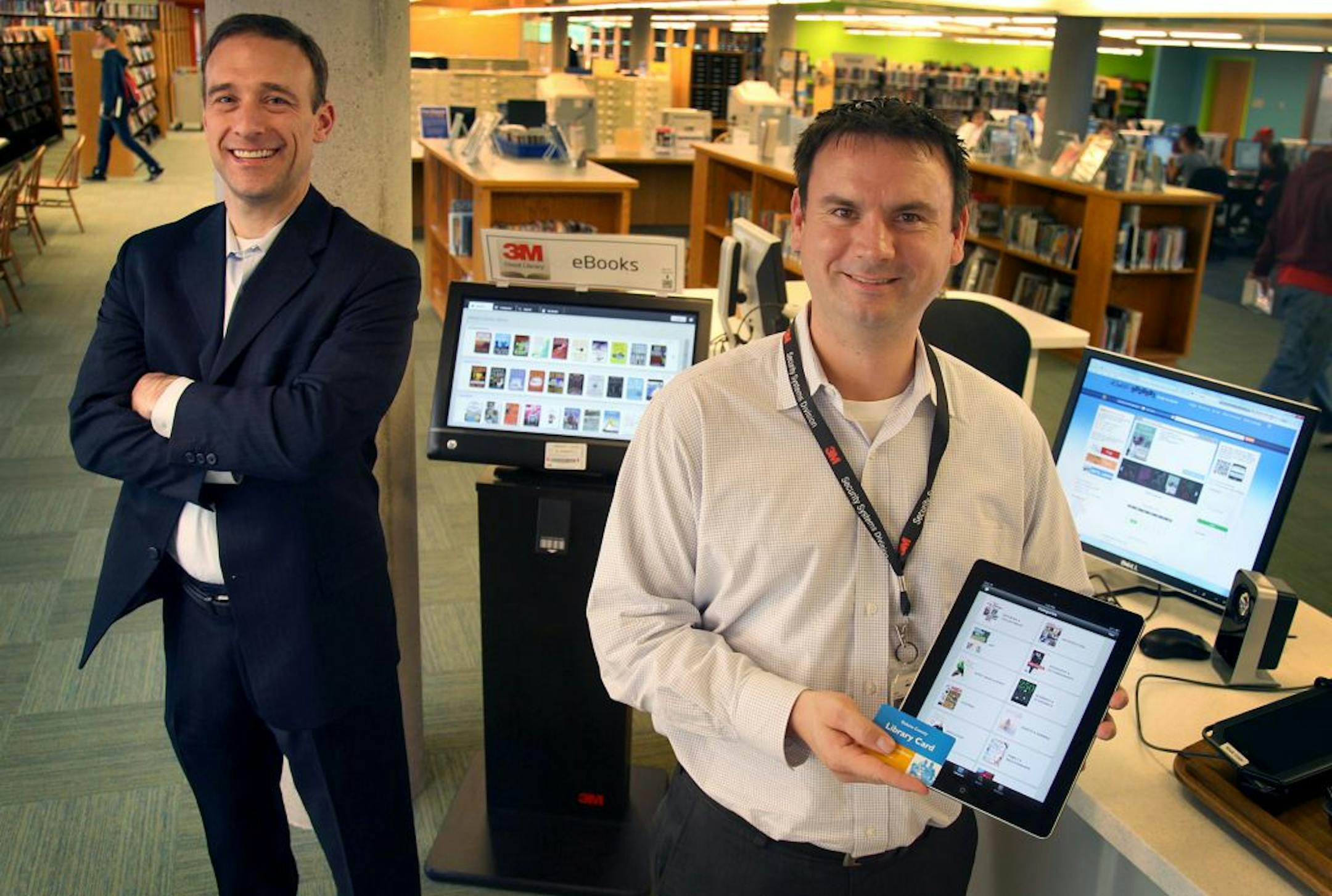 3M's Matt Tempelis, left, and Tom Mercer, stood near the Wescott Library's "Cloud Library" that they devloped, Monday, November 19, 2012 in Eagan, MN. 3M has launched the 3M Cloud Library for libraries in Dakota, Ramsey and Washington Counties. They will make 225,000 eBooks available to 1.4 million Minnesotans. It was launched in April and is now going nationwide. 3M also developed handheld eReaders for libraries to lend to their patrons. (ELIZABETH FLORES/STAR TRIBUNE) ELIZABETH FLORES � eflore