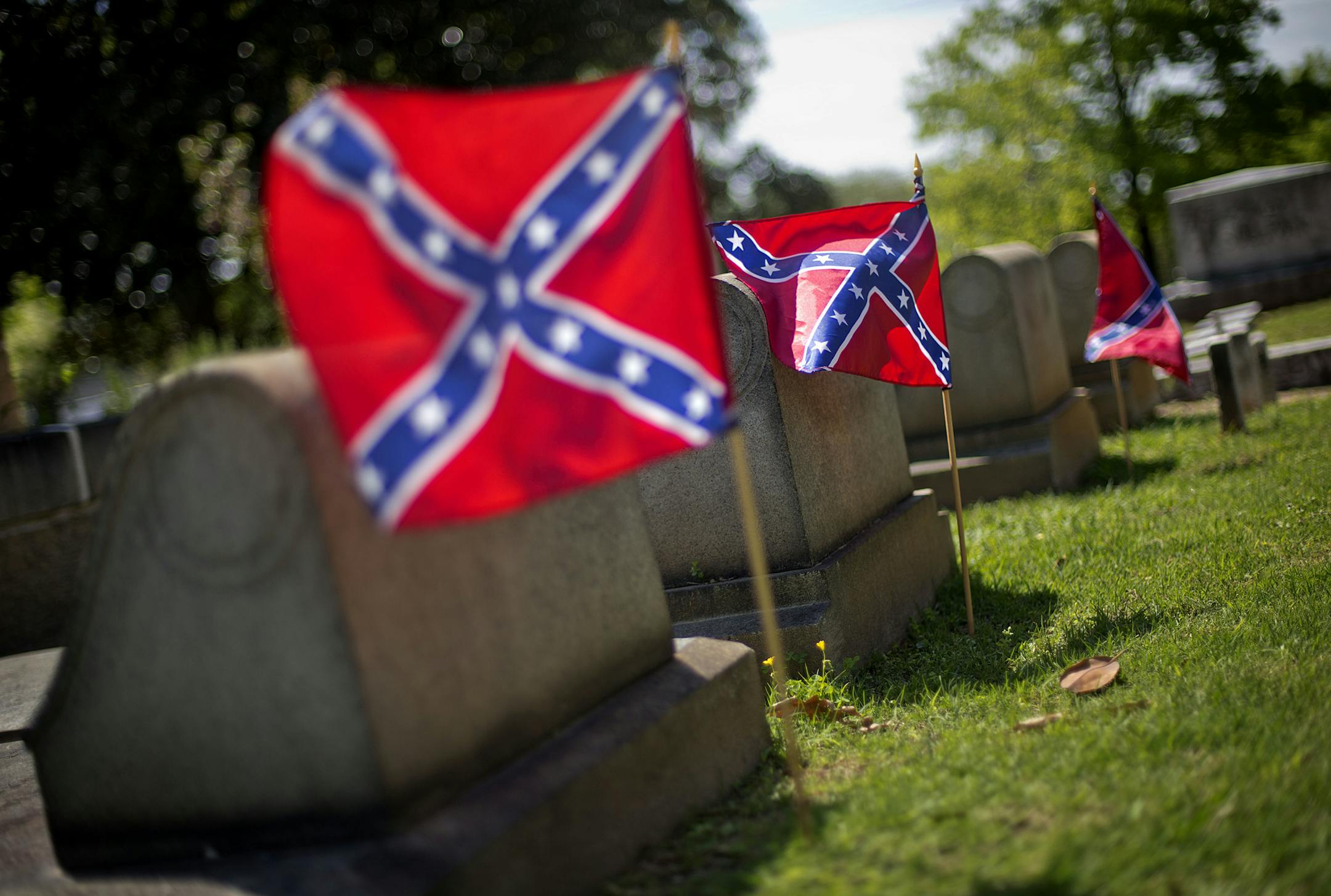 FILE - In this April 22, 2013, file photo, Confederate flags are planted next to the graves of Confederate soldiers in Oakland cemetery in Atlanta. A Georgia lawmaker on Monday, March 27, 2017, defended his proposal asking House colleagues to recognize "Confederate History Month," but black lawmakers charge it glorifies a time when slavery was acceptable. (AP Photo/David Goldman, File) ORG XMIT: GADG106