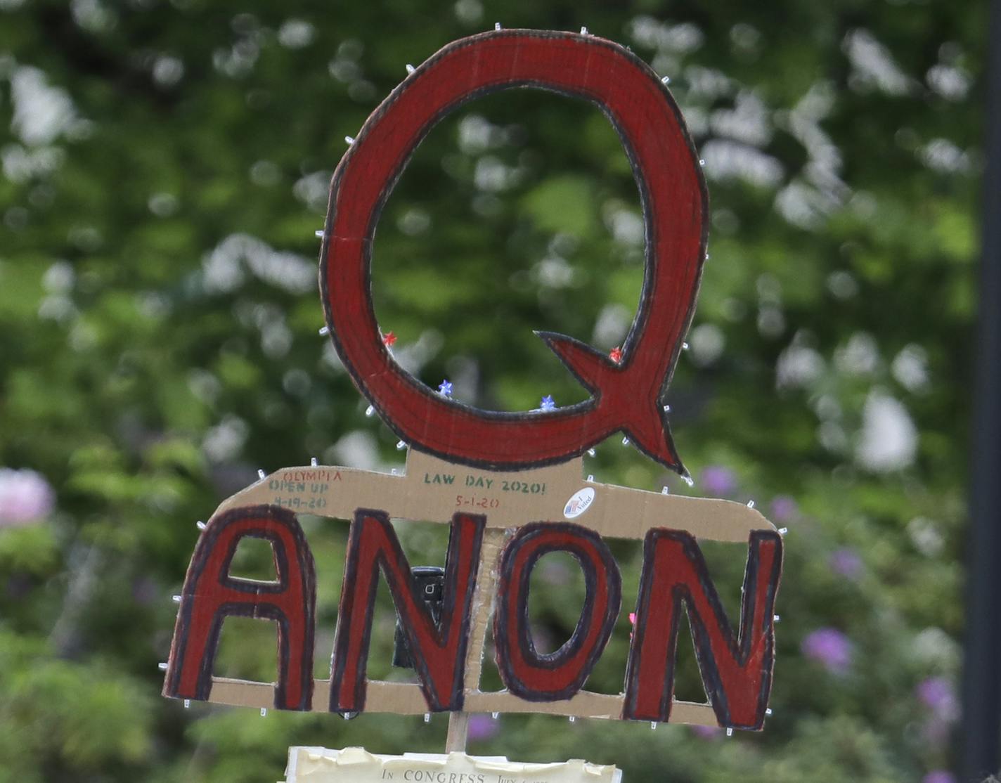 FILE - In this May 14, 2020 file photo, a person carries a sign supporting QAnon at a protest rally in Olympia, Wash. Walmart, Amazon and other corporate giants donated money to a Tennessee state lawmaker's re-election campaign after she used social media to amplify and promote the QAnon conspiracy theory. That's according to an Associated Press review of campaign finance records and online posts by Republican state Rep. Susan Lynn. (AP Photo/Ted S. Warren, File)