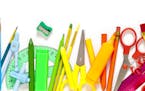 Large group of rainbow colored school supplies coming from the top and bottom of the frame shot from above against white background leaving a useful c