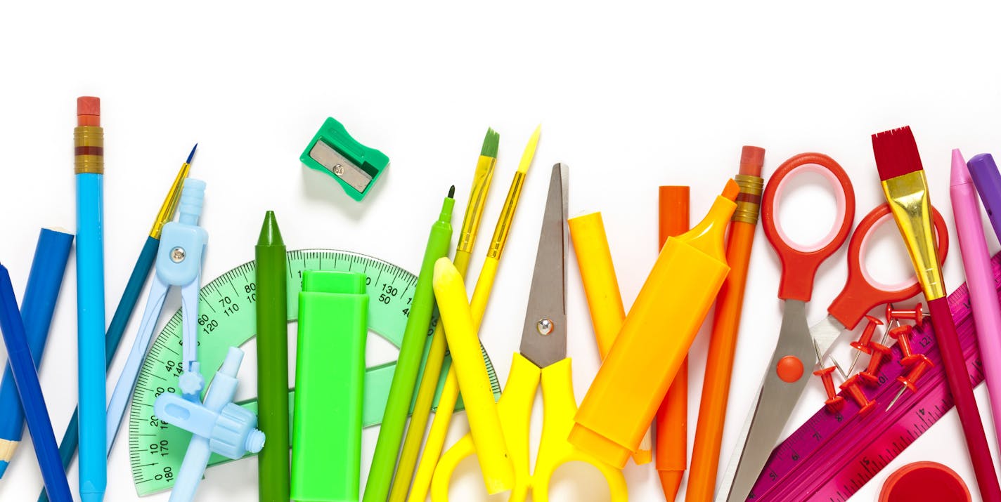 Large group of rainbow colored school supplies coming from the top and bottom of the frame shot from above against white background leaving a useful copy space at the center. The composition includes crayons, paper clips, color pencil, paintbrushes, watercolors, pencil sharpener, scissors, compass, ruler, and pushpins. DSRL studio photo taken with Canon EOS 5D Mk II and Canon EF 100mm f/2.8L Macro IS USM