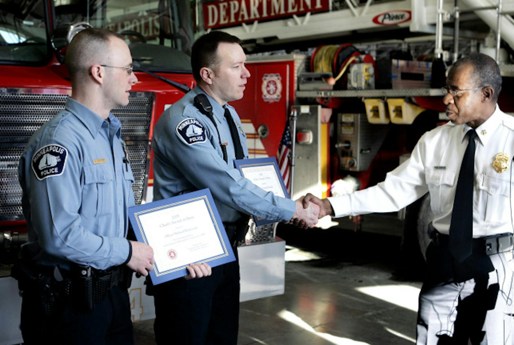 From the left, Minneapolis police officers Michael Honeycutt and George Warzinik received awards of merit on Friday from Minneapolis Fire Chief Alex Jackson during a ceremony at Fire Station 14. The officers helped alert and save 21 people from a fire early Wednesday.