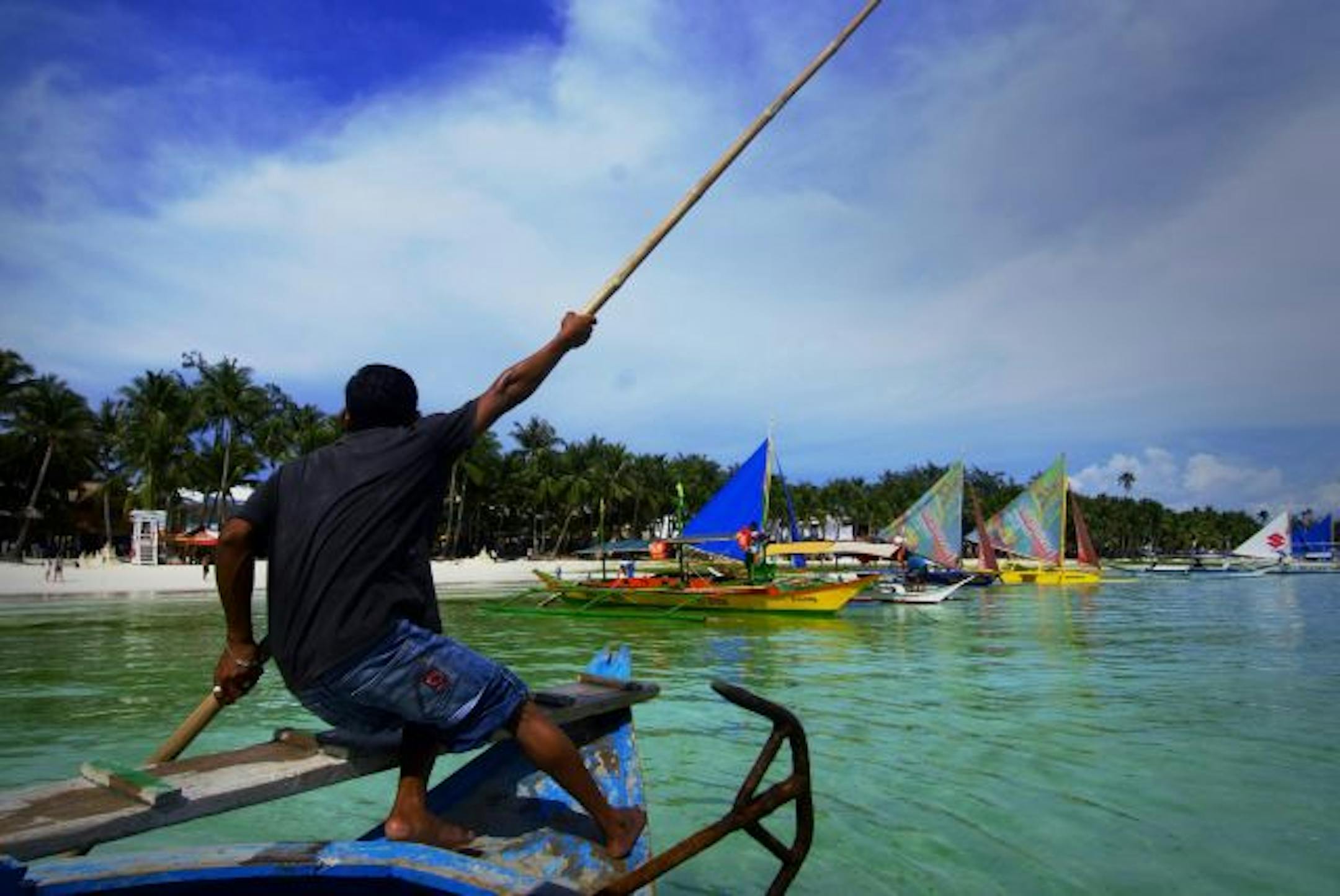 A man steers his boat off the beach on Boracay Island, Philippines.