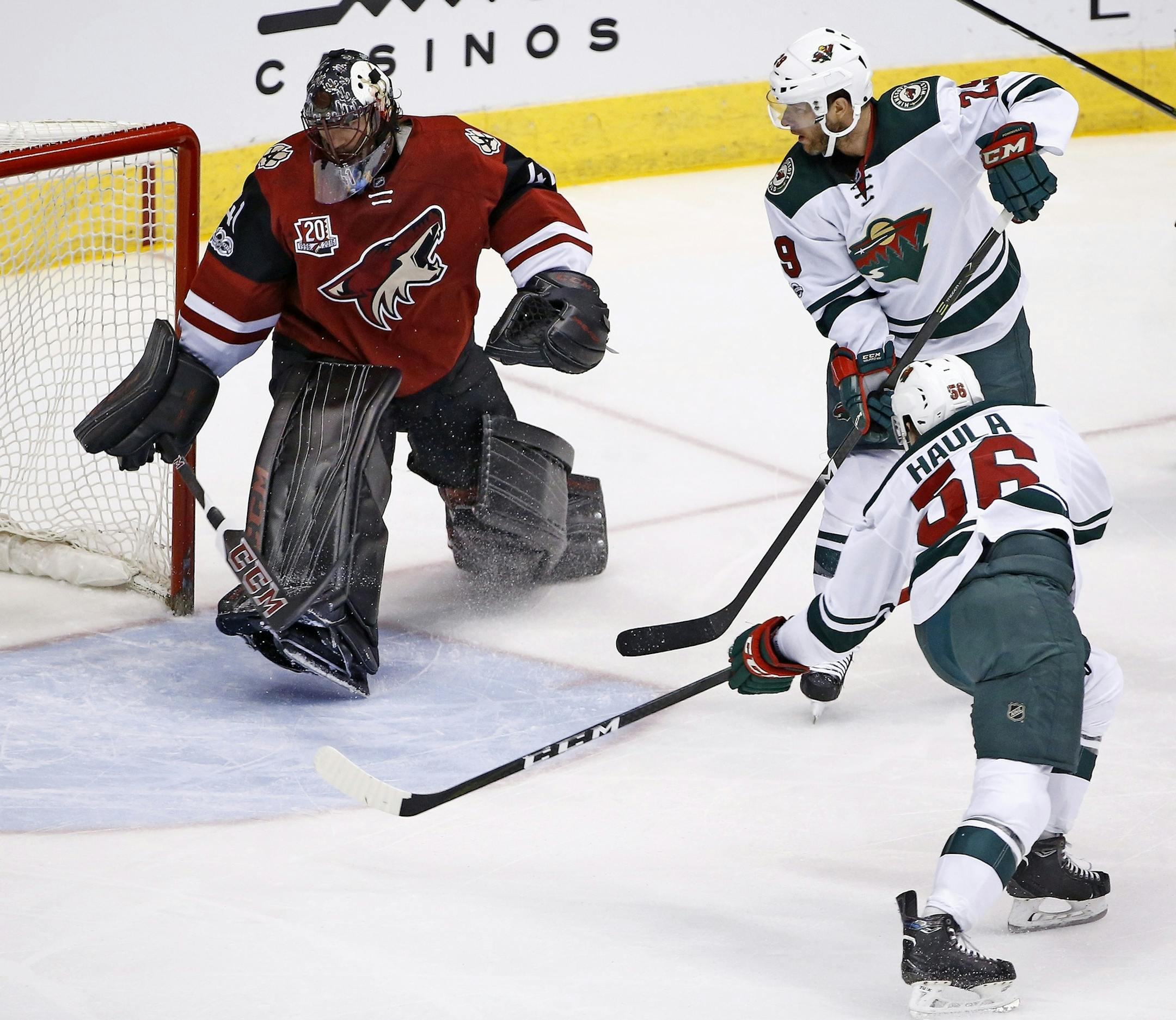 Minnesota Wild's Erik Haula, right, scores a goal on a turnover by Arizona Coyotes' Mike Smith, left, as Wild's Jason Pominville, top right, watches during the first period of an NHL hockey game Saturday, April 8, 2017, in Glendale, Ariz. (AP Photo/Ross D. Franklin)