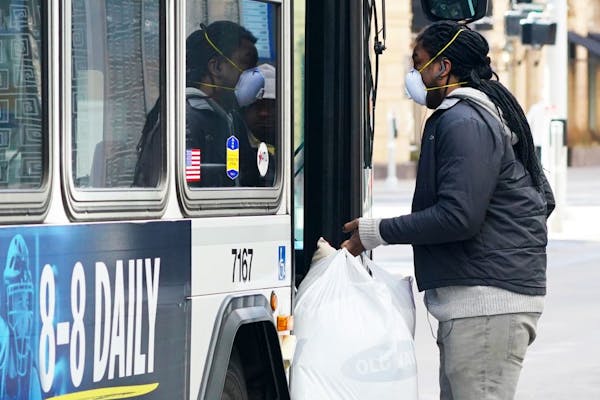 A man wore a protective mask as he ran with bags of groceries to a bus Saturday on Nicollet Mall.