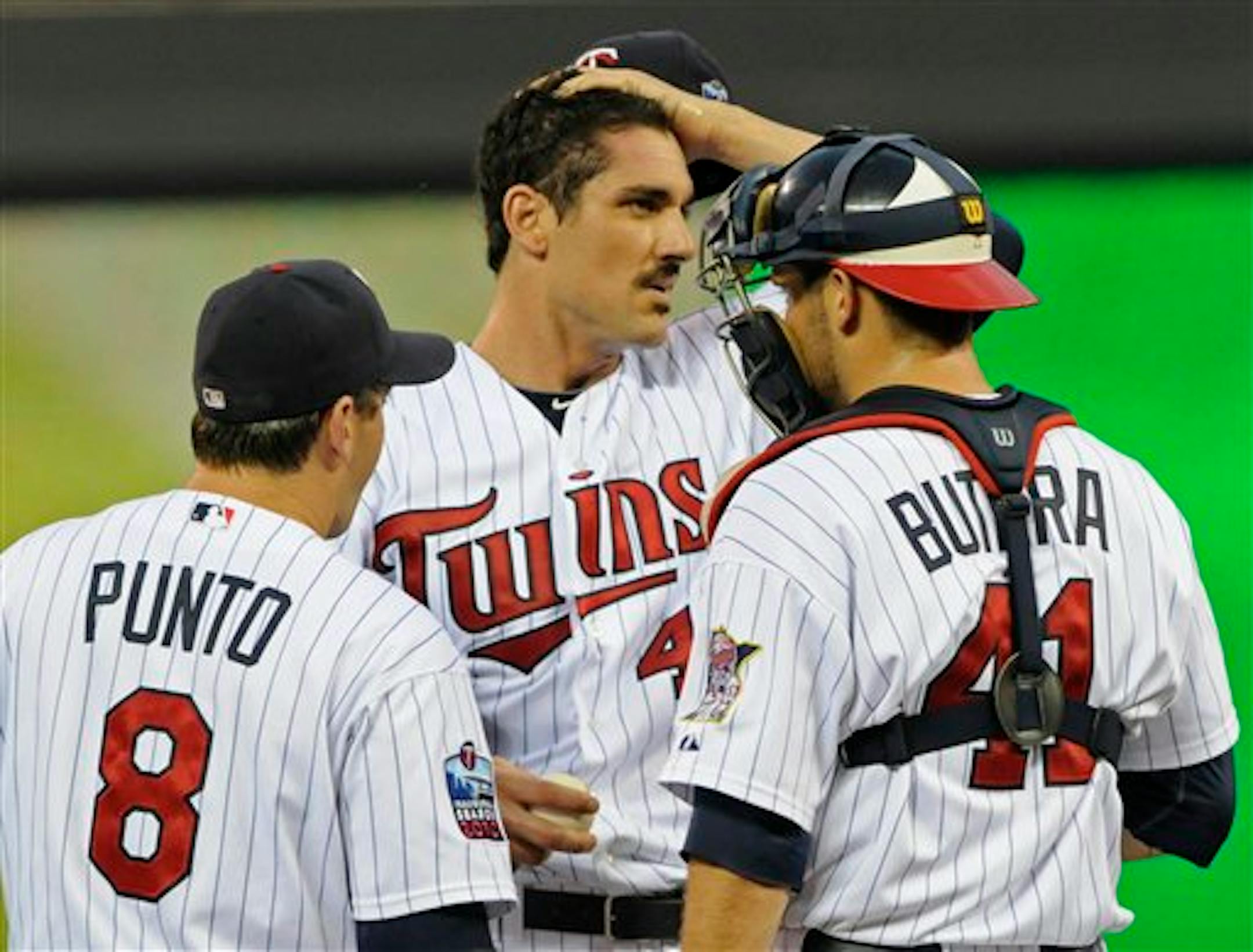 Minnesota Twins pitcher Carl Pavano, center, gets a visit from shortstop Nick Punto and catcher Drew Butera after giving up two runs to the Chicago White Sox in the first inning of a baseball game Thursday, Aug. 19, 2010, in Minneapolis. (AP Photo/Jim Mone)