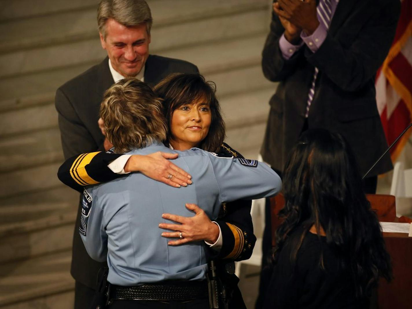 New Minneapolis Police Chief Janee Harteau was swarn in Tuesday afternoon in the City Hall Routunda. Here, Harteau gets a hug from partner Holly Keegel after her daughter Lauren Harteau (right) pined the Chief's Badge on her uniform.