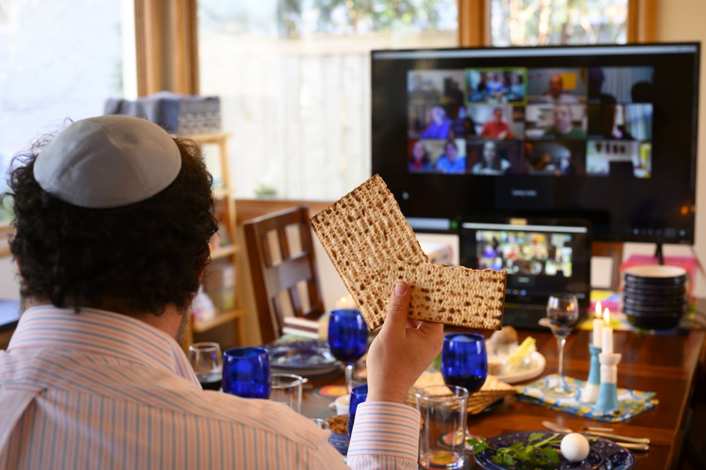 Bruce Manning held up matzo, which he just broke in half as part of Passover seder ritual, as he took part in a virtual seder alongside his family Wednesday night.