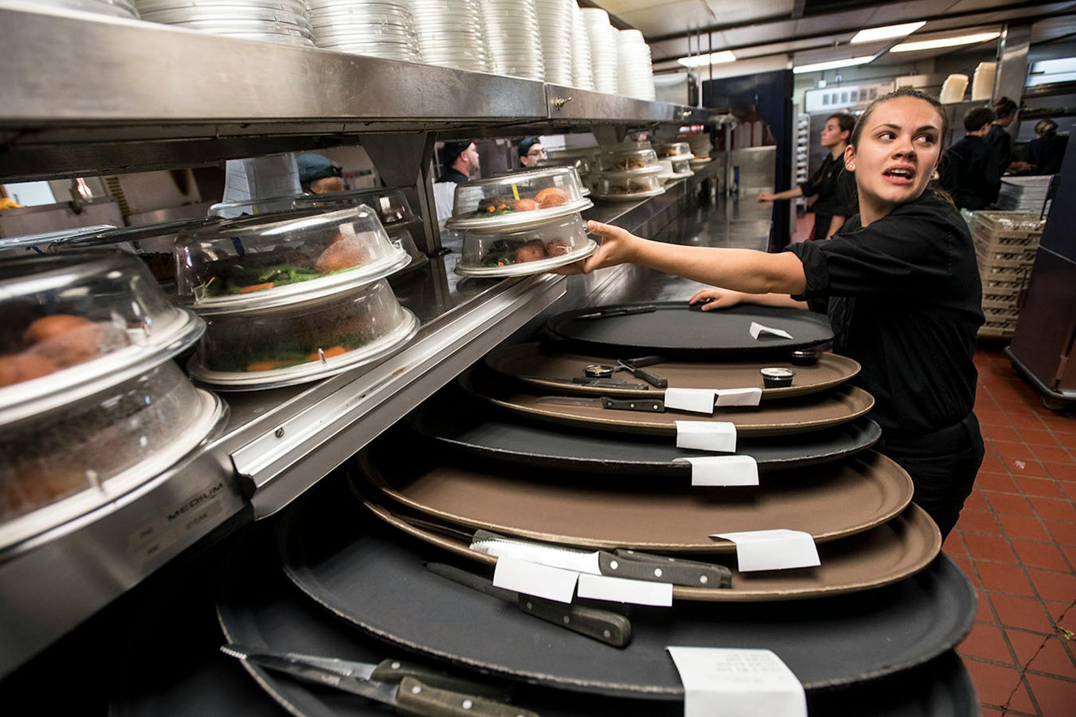 Kara Hippen, of Chanhassen, an expediter in the kitchen, placed entrees onto trays which were to be delivered by server assistants to servers in the theater.
