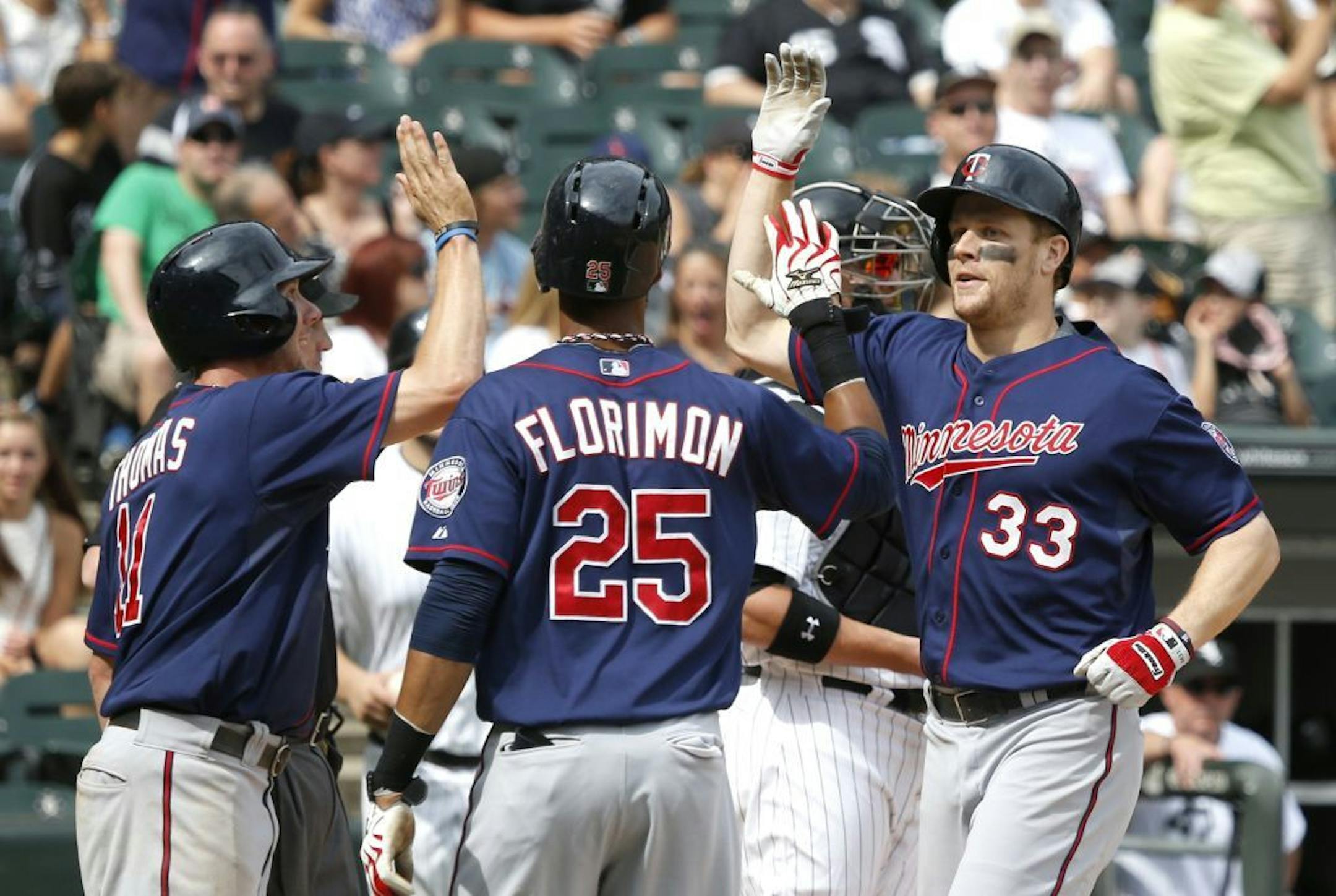 Minnesota Twins' Justin Morneau (33) is greeted at home by Clete Thomas (11) Pedro Florimon (25) after the trio and Joe Mauer scored on Morneau's grand slam off Chicago White Sox relief pitcher Nate Jones during the seventh inning of a baseball game on Friday, Aug. 9, 2013, in Chicago.
