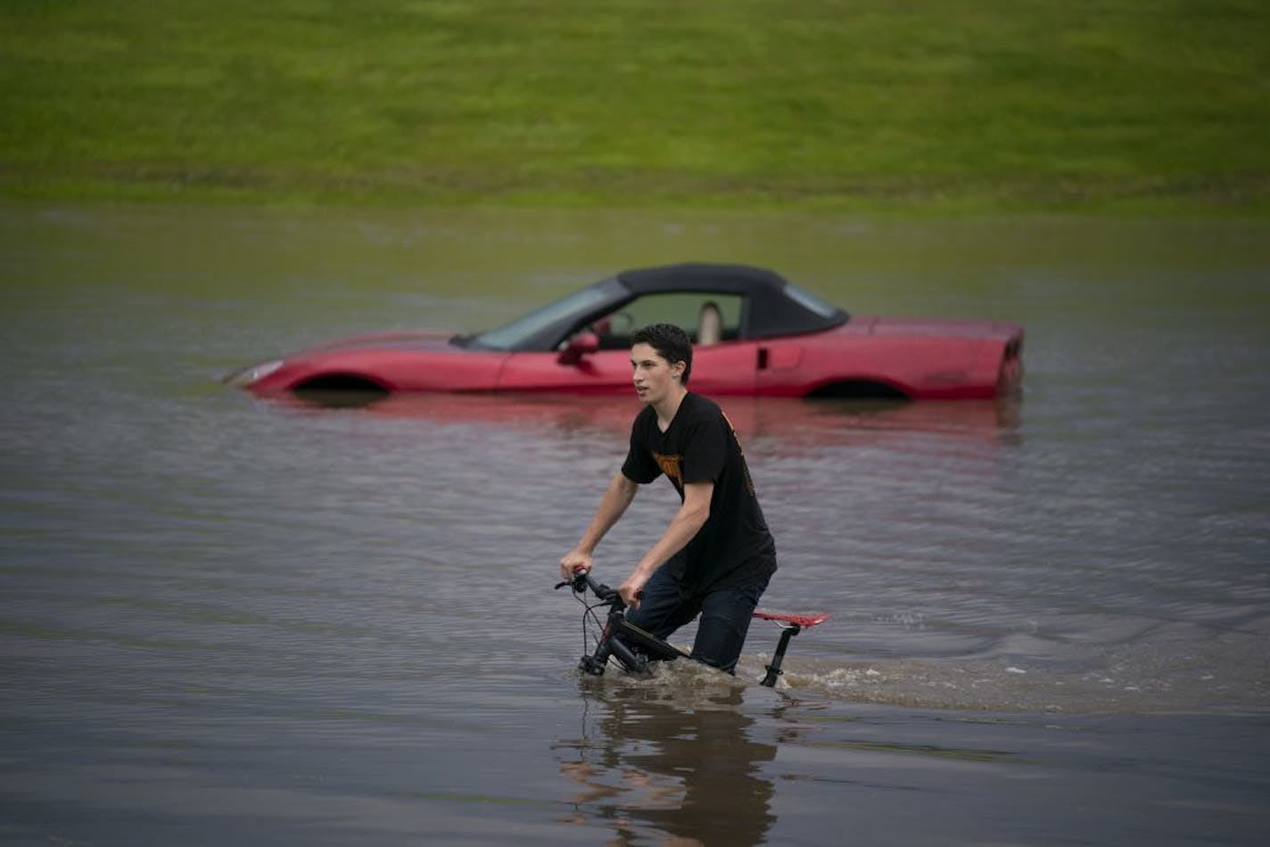 Austin Schiff pedaled past stranded vehicles next to Lakeville North High School in June. The Twin Cities reached its second-highest rainfall this summer in more than a century.