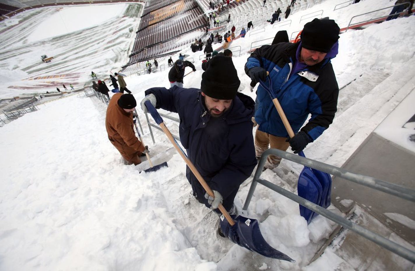 Marcos Enriquez, of St. Paul, left and Roger Aarmburse, of Rochester, shoveled snow into piles for removal from the upper deck seating at TCF Stadium. This was the first time in the stadium for both men.