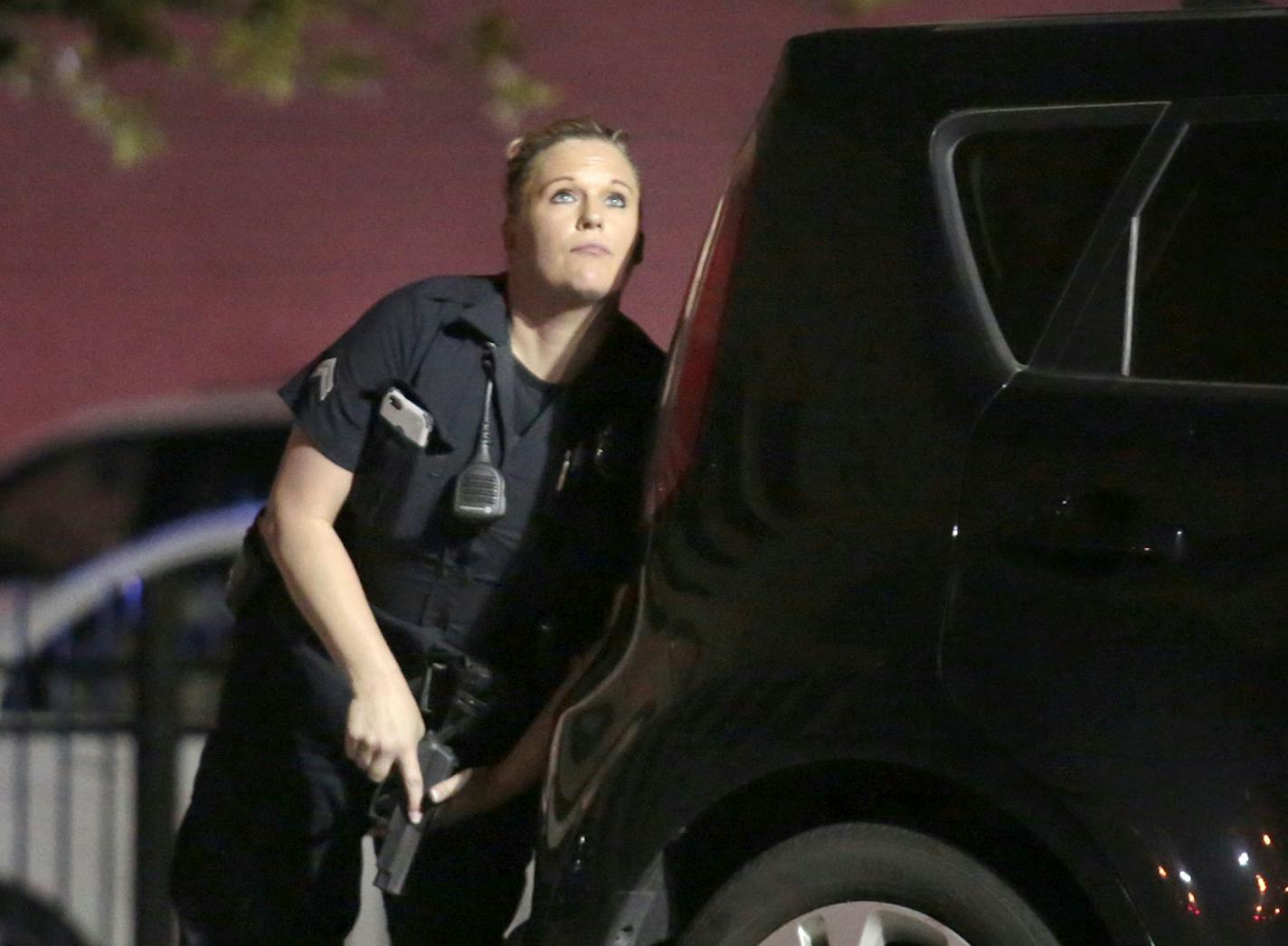 A police officer looks up while standing behind a vehicle, as police responded to shots being fired during a protest over recent fatal shootings by police in Louisiana and Minnesota, Thursday, July 7, 2016, in Dallas. Snipers opened fire on police officers during protests; several officers were killed, police said.