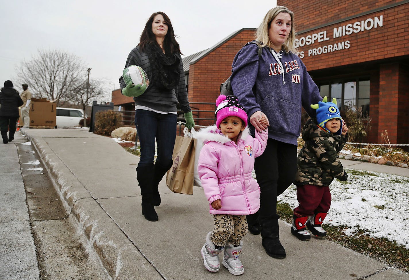 Kelli Ray of St. Paul walks with her two children Jakobe, 3, right, and Leette, 2, followed by volunteeer Randi DeMario carrying a turkey and the fixings Tuesday, Nov. 25, 2014, at Union Gospel Mission in St. Paul, MN. Ray, who works full time and lives pay check to pay check says "we rely on this" for thanksgiving. Sometimes Ray says money is so tight, she has to decide whether to pay the electric bill or buy food. Demario is a student at MCTC but decided the best lessons Tuesday could be learn