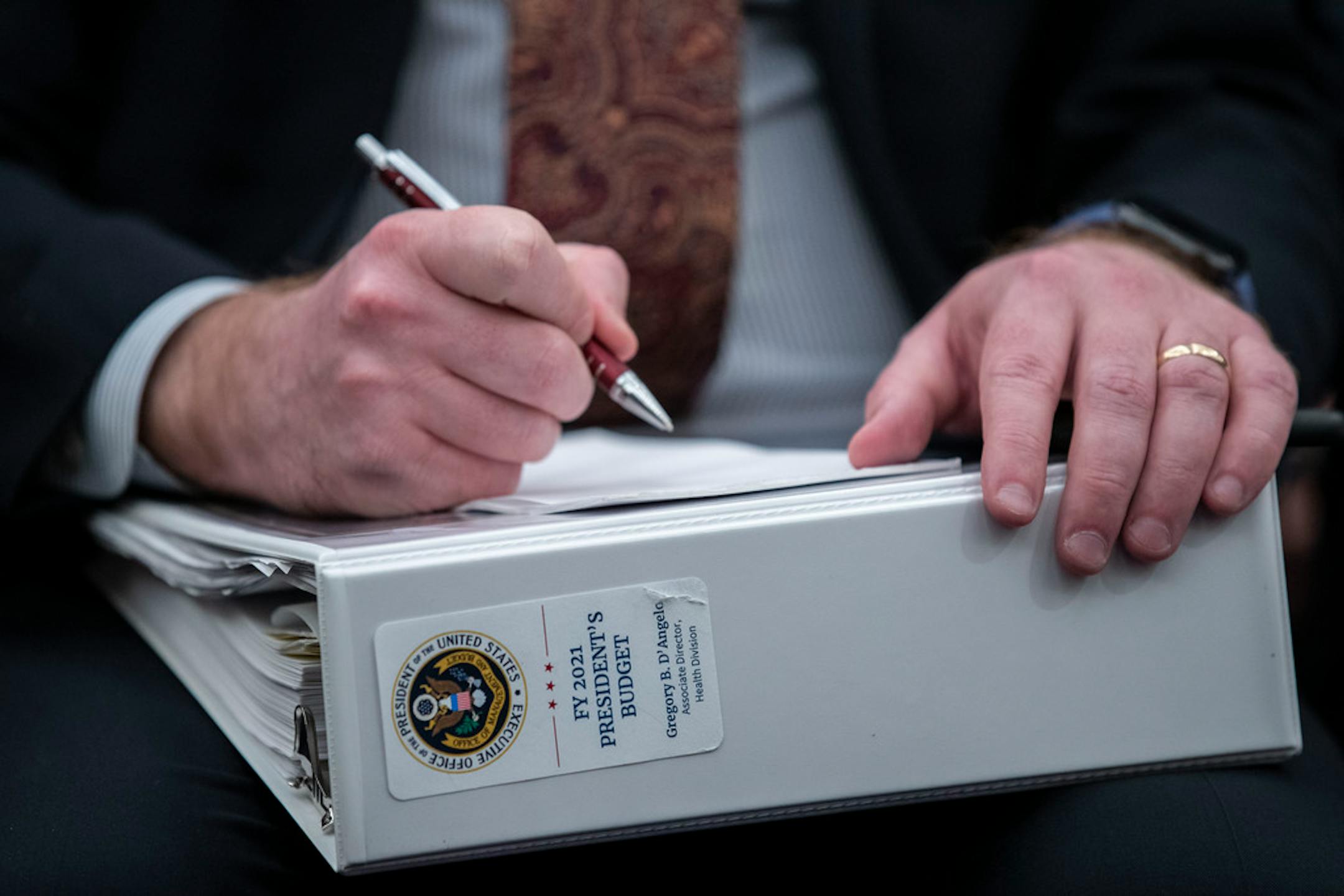 An aide holds a copy of the President's Budget for 2021 at a hearing of the House Budget Committee, Wednesday, Feb. 12, 2020.