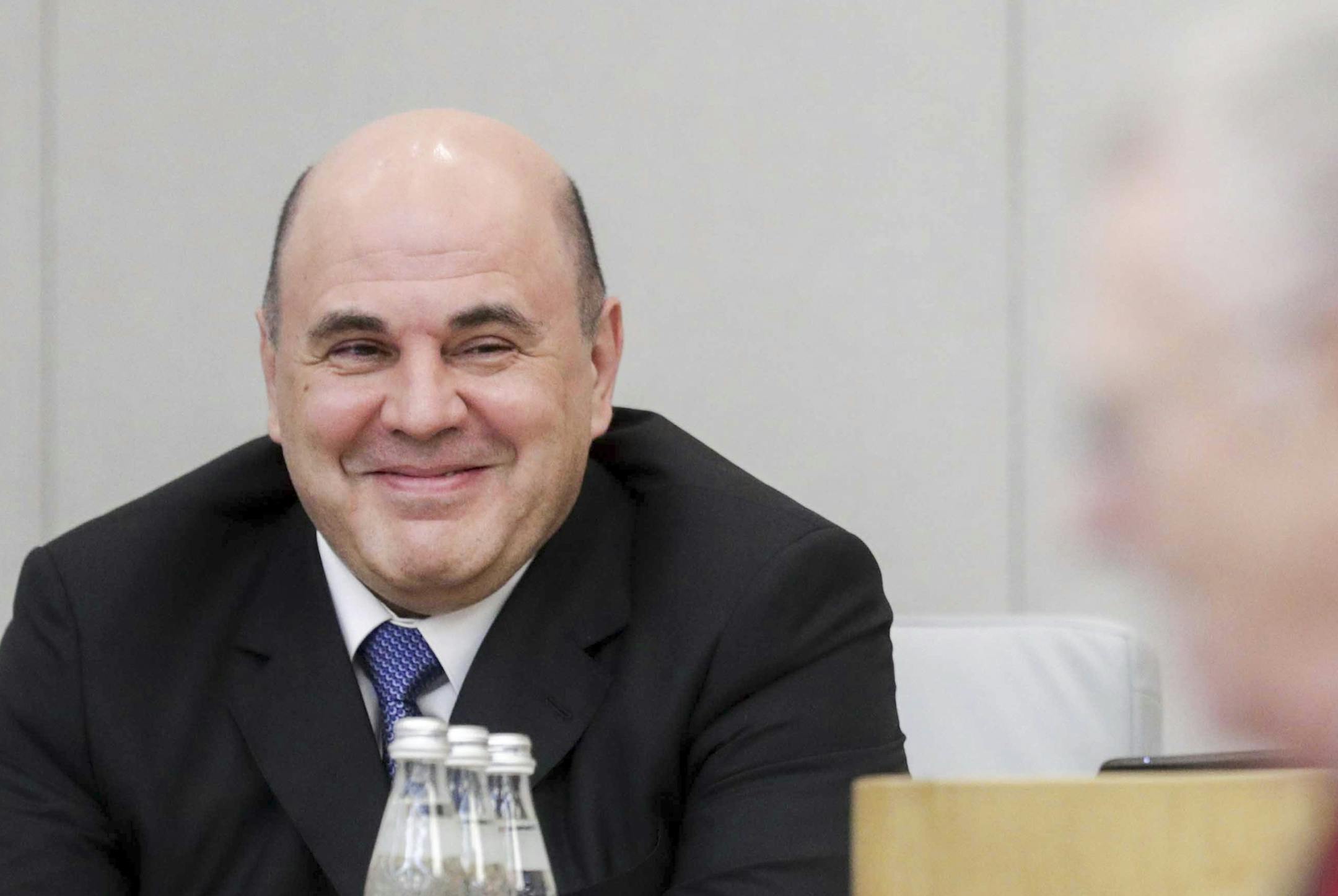 In this handout photo provided by The State Duma, The Federal Assembly of The Russian Federation, Russian Tax Service chief Mikhail Mishustin, who was nominated to replace Medvedev, smiles listening Russian Liberal Democratic Party leader Vladimir Zhirinovsky's speech during a session at the State Duma, the Lower House of the Russian Parliament in Moscow, Russia, Thursday, Jan. 16, 2020. 53-year-old Mishustin, the longtime chief of Russia's tax service, was tapped for the post by President Vladi