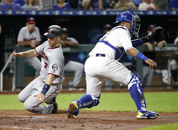 Minnesota Twins' Joe Mauer (7) beats a tag by Kansas City Royals catcher Salvador Perez to score on a single by Jake Cave during the fifth inning of a
