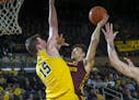 Michigan center Jon Teske (15) defends a shot attempt from Minnesota guard Amir Coffey, right, in the first half of an NCAA college basketball game at