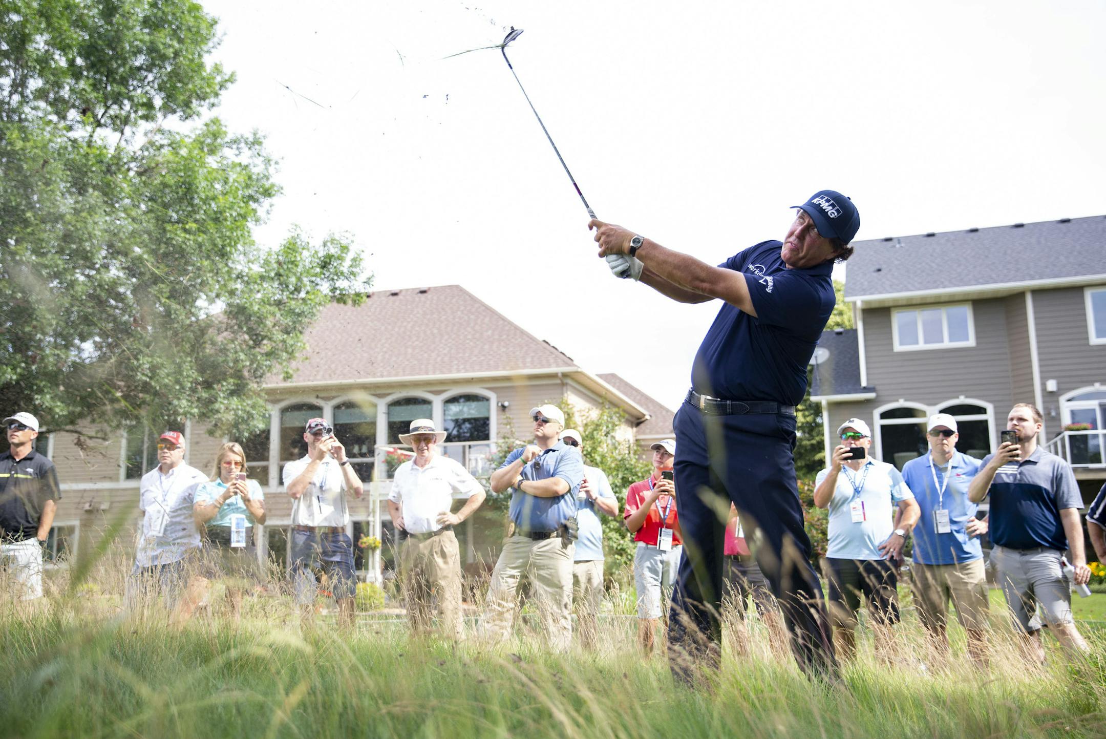 Phil Mickelson hits a ball out of the tall grass surrounded by spectators. ALEX KORMANN &#xa5; alex.kormann@startribune.com Competitors for the 3M Open took to the course on Thursday for the first day of the PGA tour event. Notable players include Phil Mickelson, Brooks Koepka, Patrick Reed and Bryson DeChambeau.