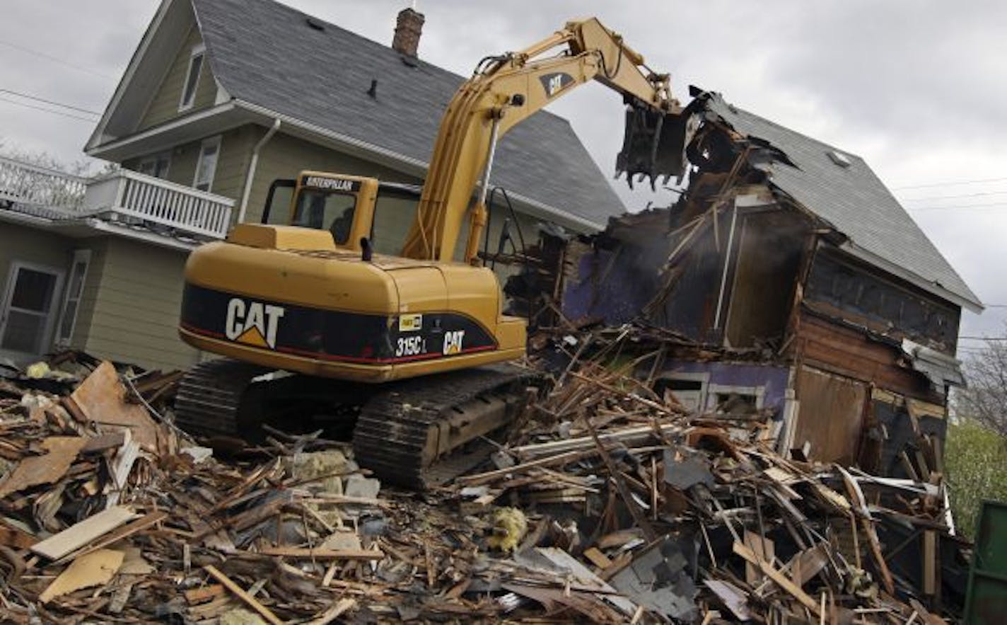 Workers from Rayco Excavating tore down a house at 677 Canton St. in St. Paul on Tuesday. It is one of more than 100 homes that the city expects to demolish this year. The knockdown process takes three days and leaves an empty lot.