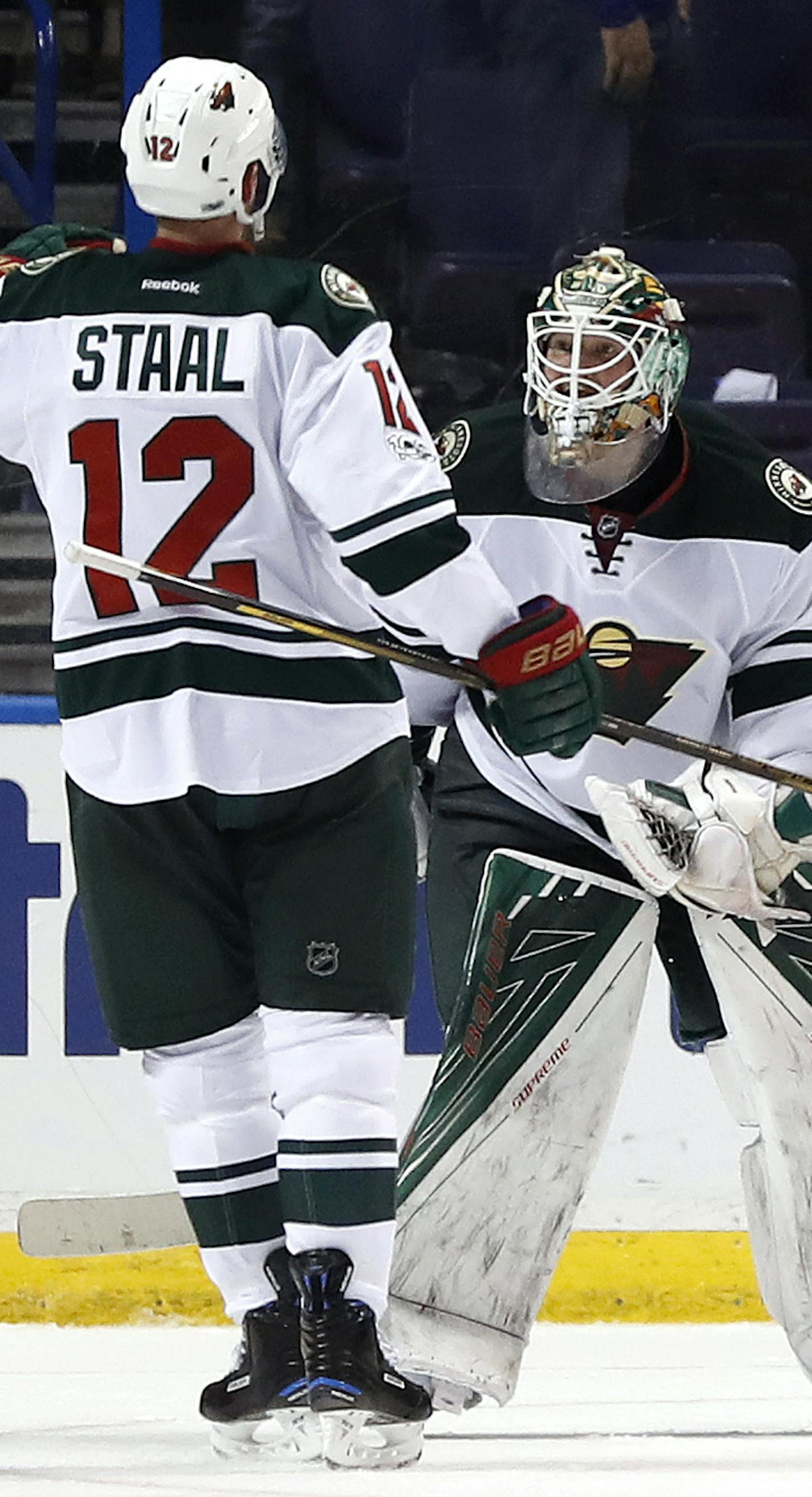 Minnesota Wild goalie Devan Dubnyk, right, and Eric Staal celebrate following the team's 2-0 victory over the St. Louis Blues in Game 4 of an NHL hockey first-round playoff series Wednesday, April 19, 2017, in St. Louis. (AP Photo/Jeff Roberson)