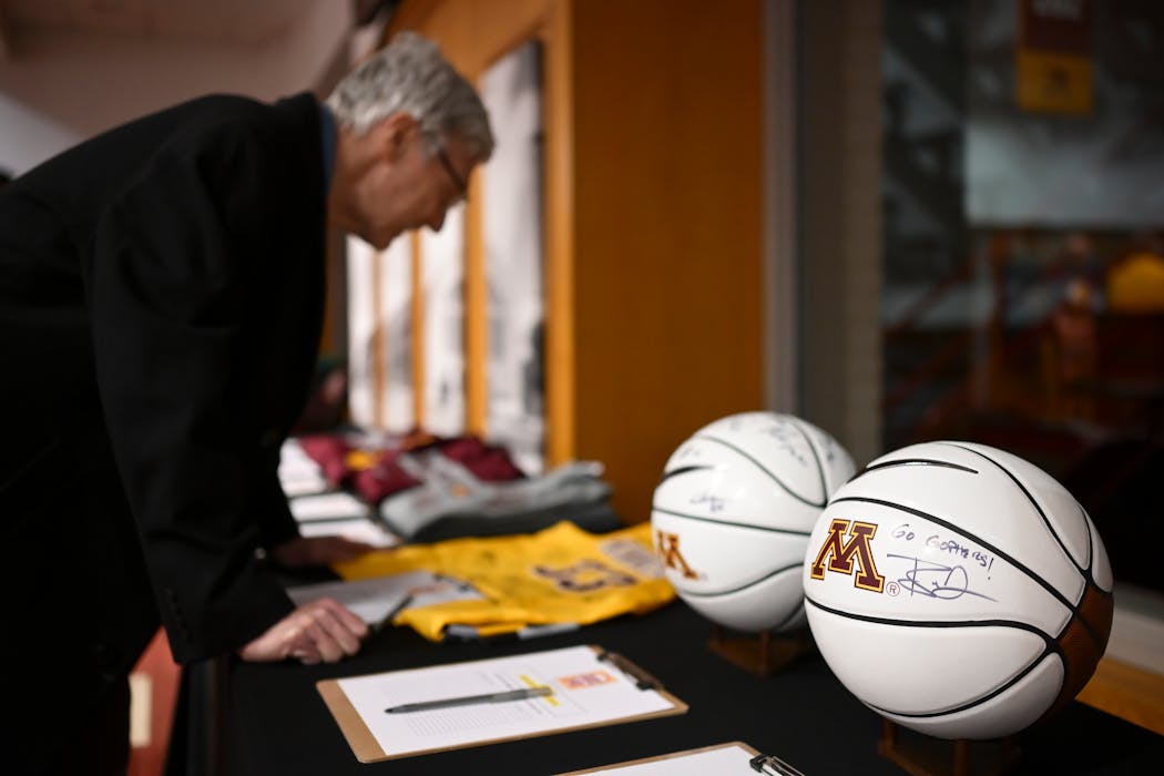 Booster club member Michael Barg, of Bloomington, looks to place bids for signed Gophers memorabilia at Williams Arena.