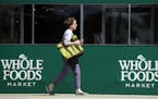 A shopper leaves a Whole Foods Market in Northbrook, Ill., Saturday, June 17, 2017. Amazon is buying Whole Foods in a deal valued at about $13.7 billi