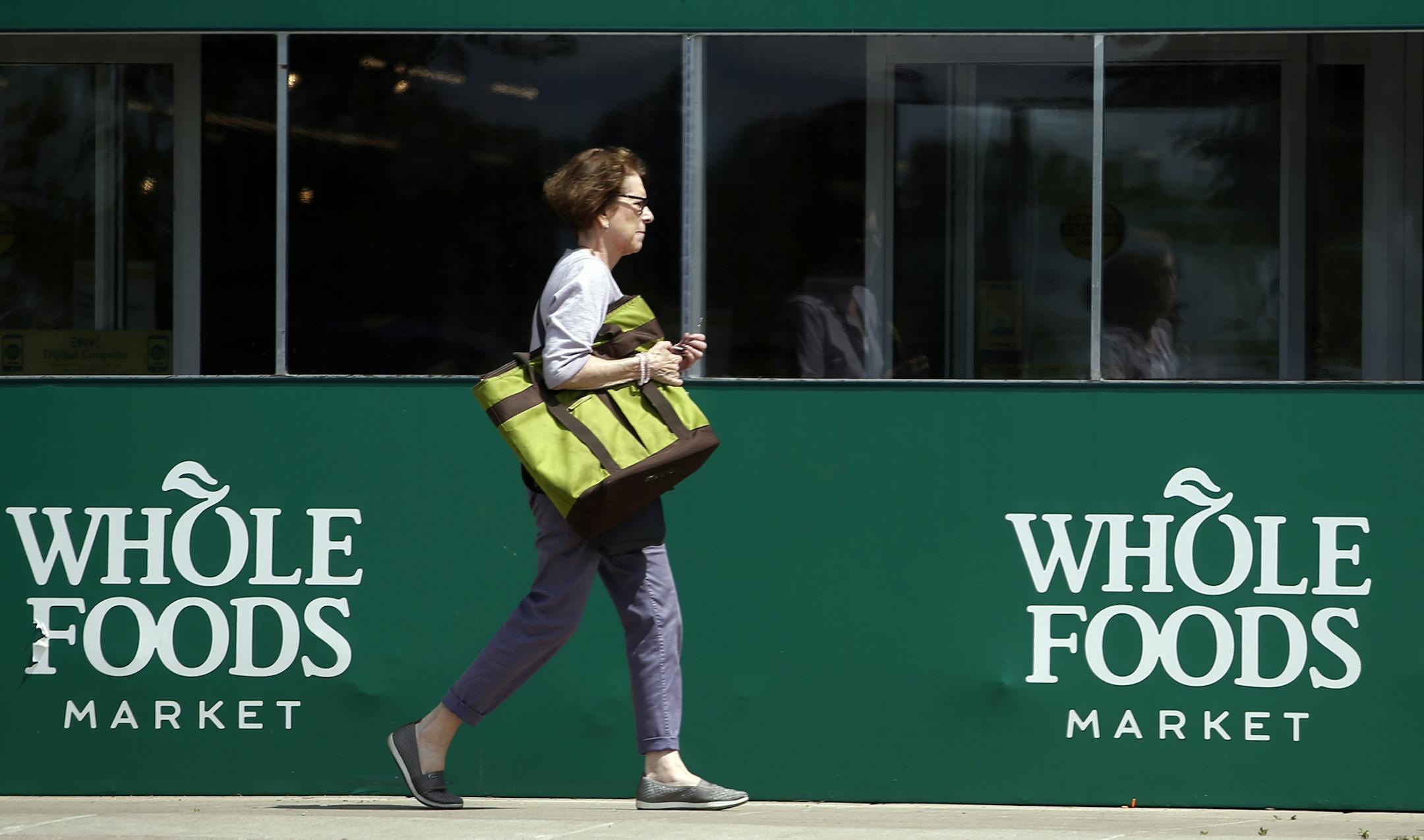 A shopper leaves a Whole Foods Market in Northbrook, Ill., Saturday, June 17, 2017. Amazon is buying Whole Foods in a deal valued at about $13.7 billion, a strong move to expand its growing reach into groceries. (AP Photo/Nam Y. Huh)