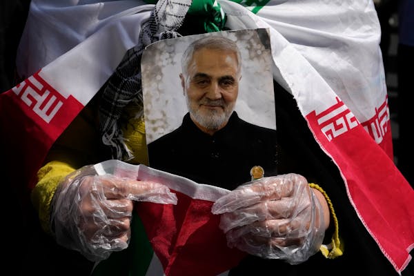 A worshipper holds a portrait of the late Iranian Revolutionary Guard Gen. Qassem Soleimani, who was killed in a U.S. drone attack in 2020 in Iraq, du