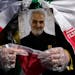 A worshipper holds a portrait of the late Iranian Revolutionary Guard Gen. Qassem Soleimani, who was killed in a U.S. drone attack in 2020 in Iraq, du