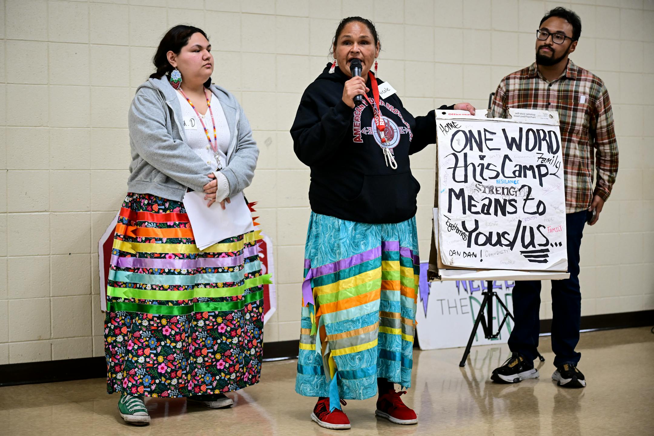 Organizer Nicole Mason, enrolled with the Red Lake Nation, center, stood with her daughter Isa Diaz and son Joe Vital as she showed a poster signed by residents of the nearby Nenookaasi encampment.