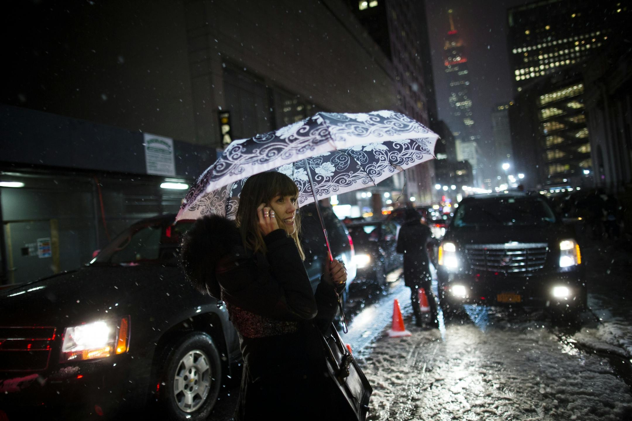 Snow falls on a pedestrian as she leaves the Rag & Bone Fall 2013 fashion collection show on 33rd Street during Fashion Week, Friday, Feb. 8, 2013, in New York. Snow began falling across the Northeast on Friday, ushering in what was predicted to be a huge, possibly historic blizzard and sending residents scurrying to stock up on food and gas up their cars.