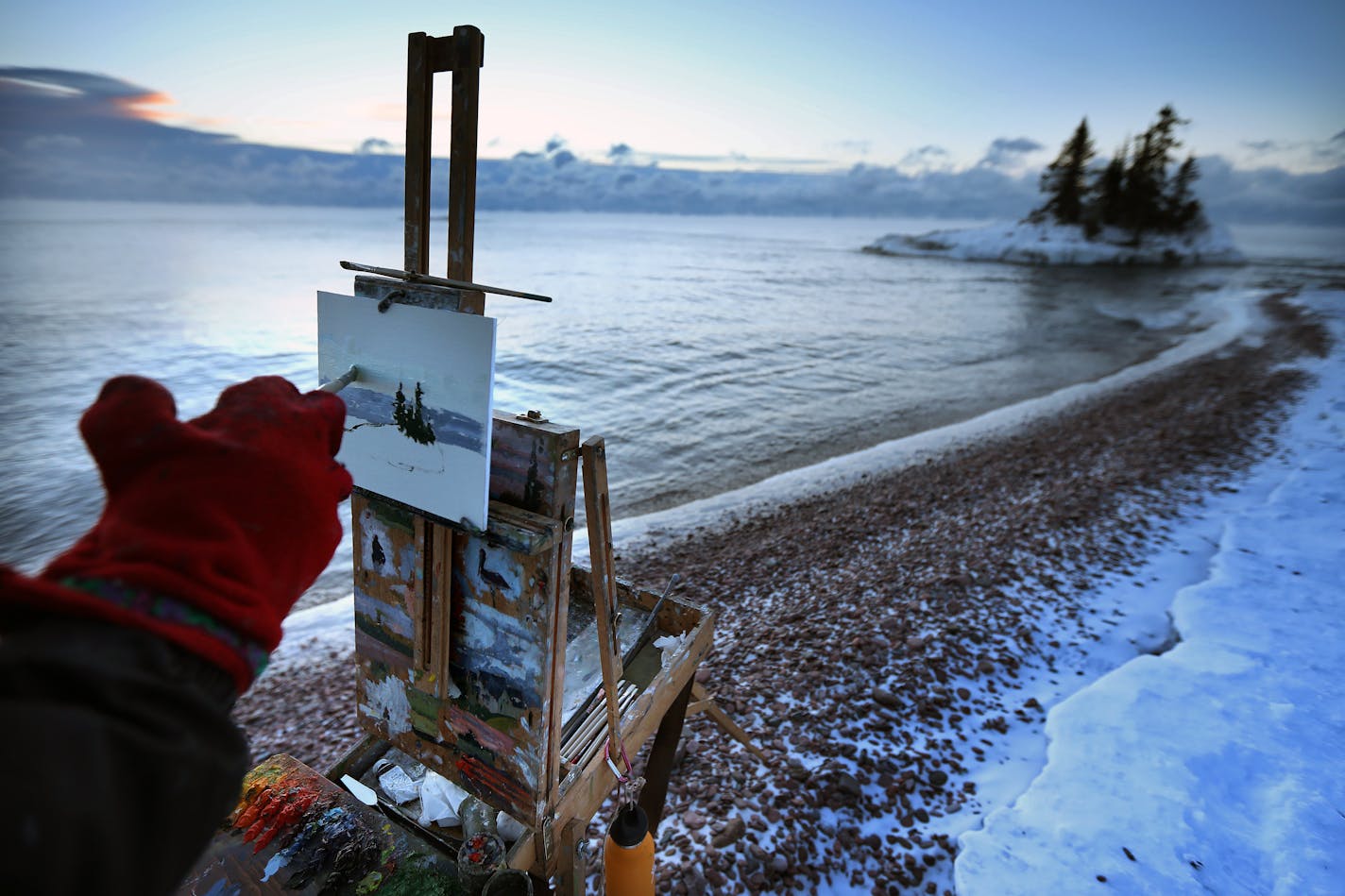 Plein Air painter Neil Sherman, ventures into the outdoors, even in the extremes, to paint and create. Dressing warm is often the biggest challenge, when it's cold Sherman paints with mittens with a hole cut into them for the brush. All the warm layers can restrict arm movement and dexterity. ]