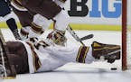Minnesota goalie Eric Schierhorn reaches to stop the puck during the first period of an NCAA college hockey semifinal match against Penn State in the 