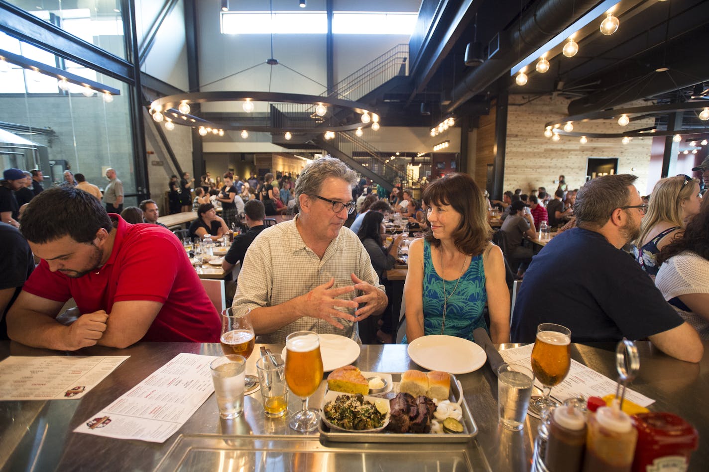 Tim Hennessy, left of center, talked to Patricia McFadden before they dug into their dinner of smoked brisket with brussels sprouts and cornbread on Friday night. ] Aaron Lavinsky ¥ aaron.lavinsky@startribune.com Restaurant review of Surly Brewing's casual beer hall and the more formal Brewer's Table. Photographed Friday, July 17, 2015 in Minneapolis.