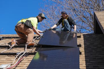 Workers from TruNorth Solar install a rooftop solar panel power system on the roof of Sheila and Richard Miller’s house in Golden Valley.