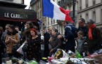 People gather in front of Le Carillon cafe, a site of the recent attacks, in Paris, Monday Nov. 16, 2015. French President Francois Hollande says the 