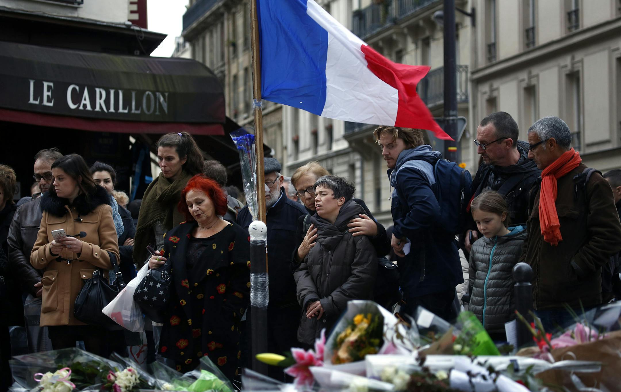 People gather in front of Le Carillon cafe, a site of the recent attacks, in Paris, Monday Nov. 16, 2015. French President Francois Hollande says the Paris attacks targeted "youth in all its diversity" and that the victims were of 19 different nationalities. (AP Photo/Jerome Delay) ORG XMIT: MIN2015111611182326