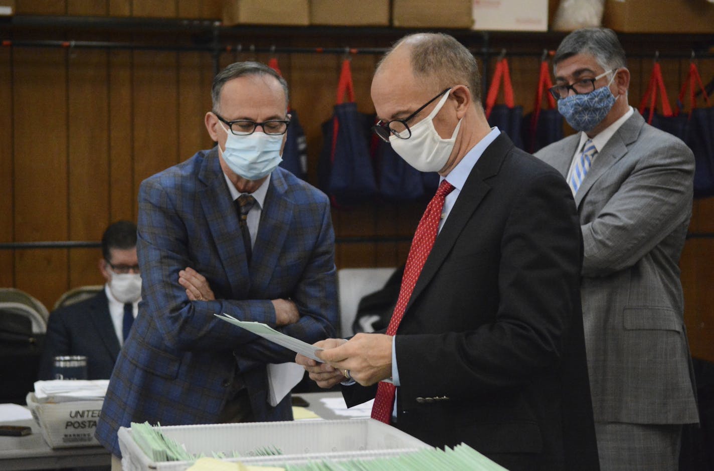 Democrat poll watcher Edward Brennan, left, and Douglas Bucklin, Republican poll watcher on behalf of President Donald Trump, right, look over provisional ballots while Assistant County Solicitor Christopher W. Hobbs, back right, oversees them at the Schuylkill County Election Bureau in Pottsville, Pa. on Tuesday, Nov. 10, 2020.