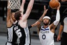 Timberwolves guard D’Angelo Russell (0) shoots past Spurs center Jakob Poeltl (25) during the second half of the Wolves’ loss on Wednesday. (AP Ph