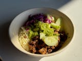 Sumac chicken rice bowl with fresh cucumbers, cabbage and spicy green herb sauce.
