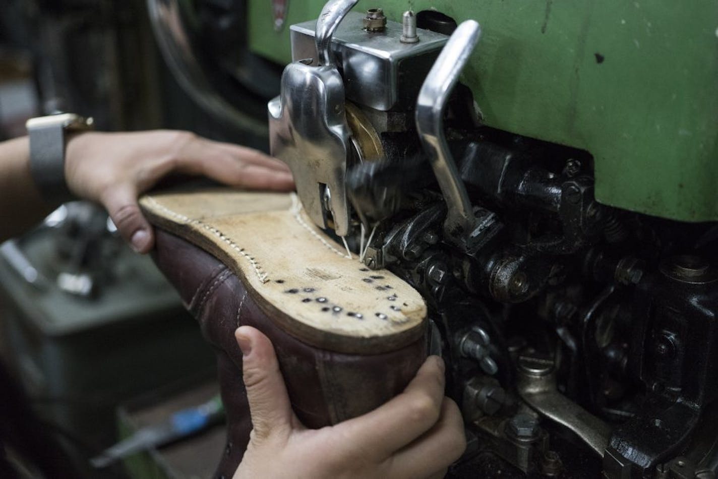 Shooli partner Meghan Flynn sews the bottom of a dress shoe at the repair shop in Minneapolis on a Landis l stitcher machine used for repairing soles.