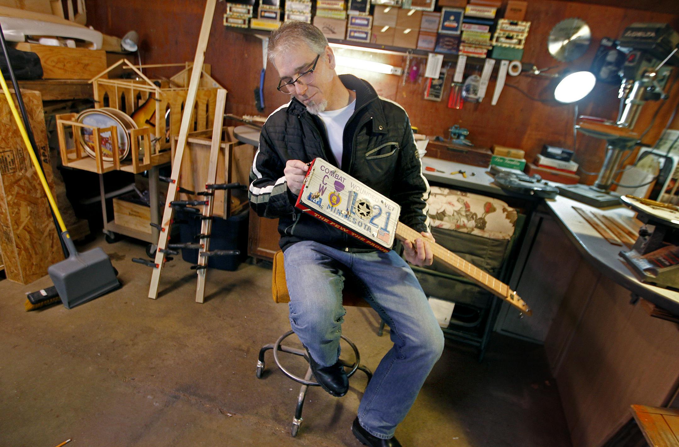 Roger Wold worked on a guitar that he made from his father's license plate from his garage, Monday, December 16, 2013 in Anoka, MN. He makes guitars that are made from cigar-boxes, toilet seats, clocks, and tin cans. The flea market vendor fished the old cigar boxes out of the trash because they looked neat, deciding a year later to turn them into musical instruments. (ELIZABETH FLORES/STAR TRIBUNE) ELIZABETH FLORES • eflores@startribune.com