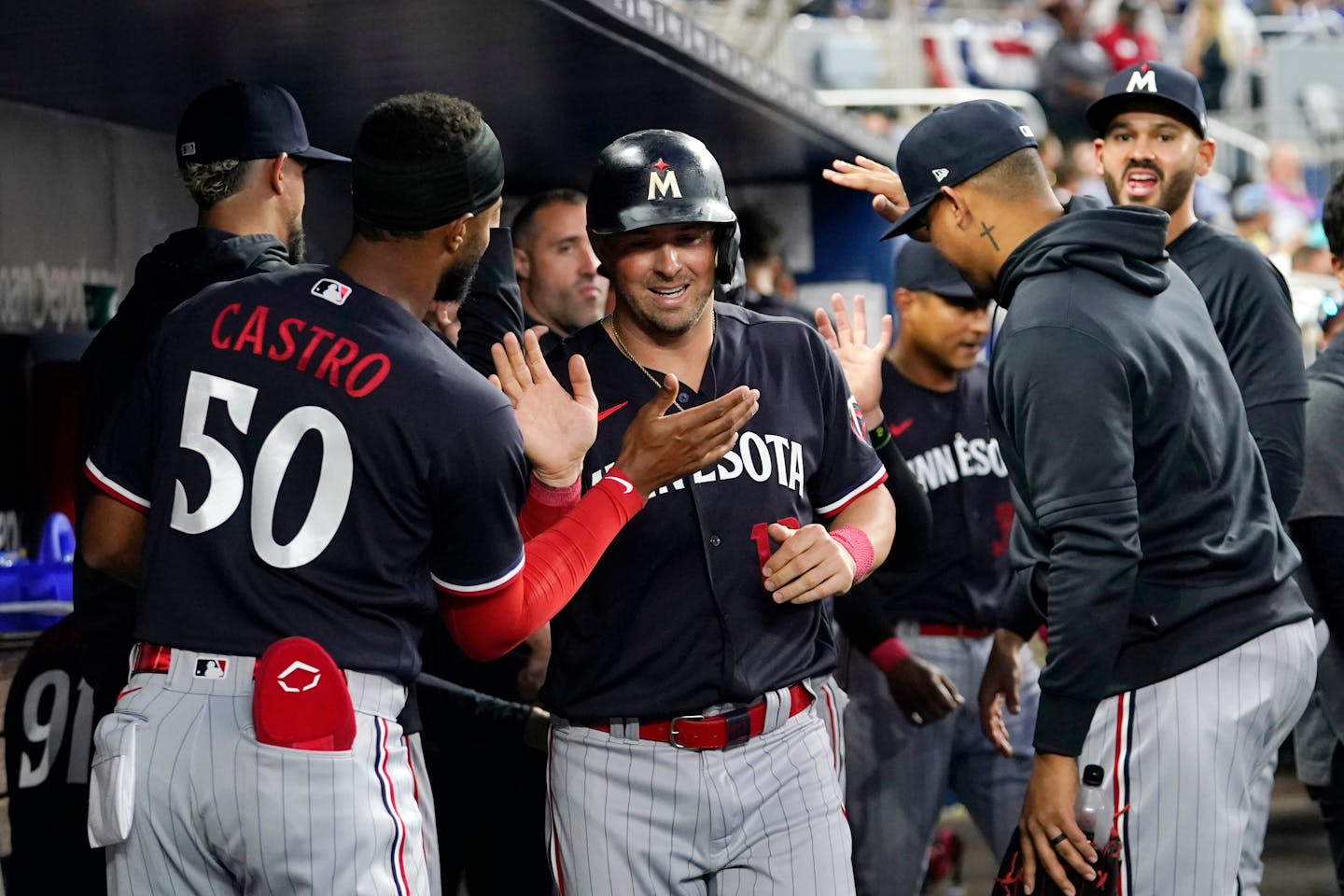 Minnesota Twins' Kyle Farmer is congratulated in the dugout after scoring on a double hit by Carlos Correa during the fourth inning of a baseball game against the Miami Marlins, Monday, April 3, 2023, in Miami. (AP Photo/Lynne Sladky)