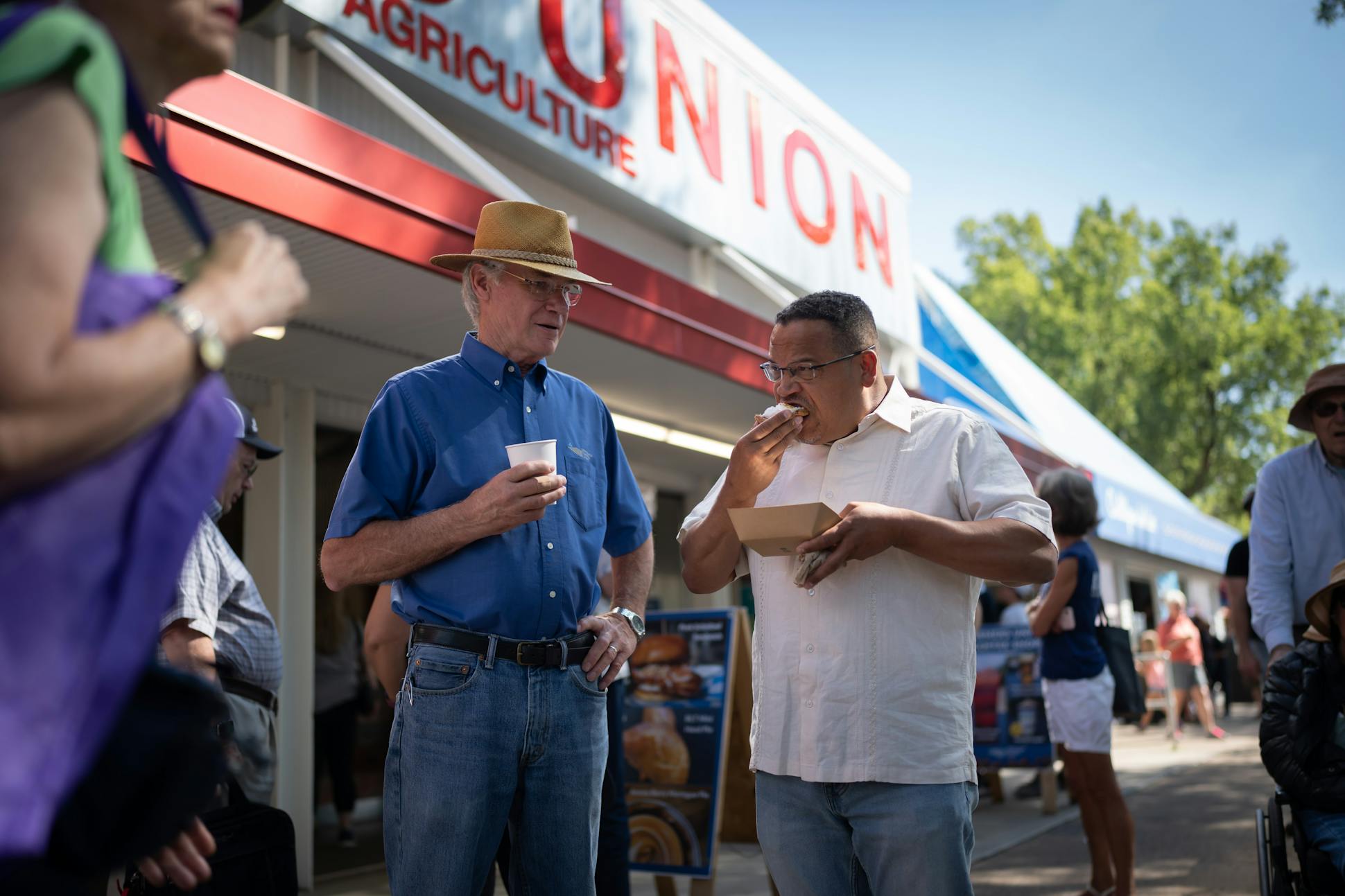 Minnesota Farmers Union President Gary Wertish, left, talked with Minnesota Attorney General Keith Ellison on Aug. 26, while Ellison ate one of the Farmers Union specialties, aronia berry meringue pie.