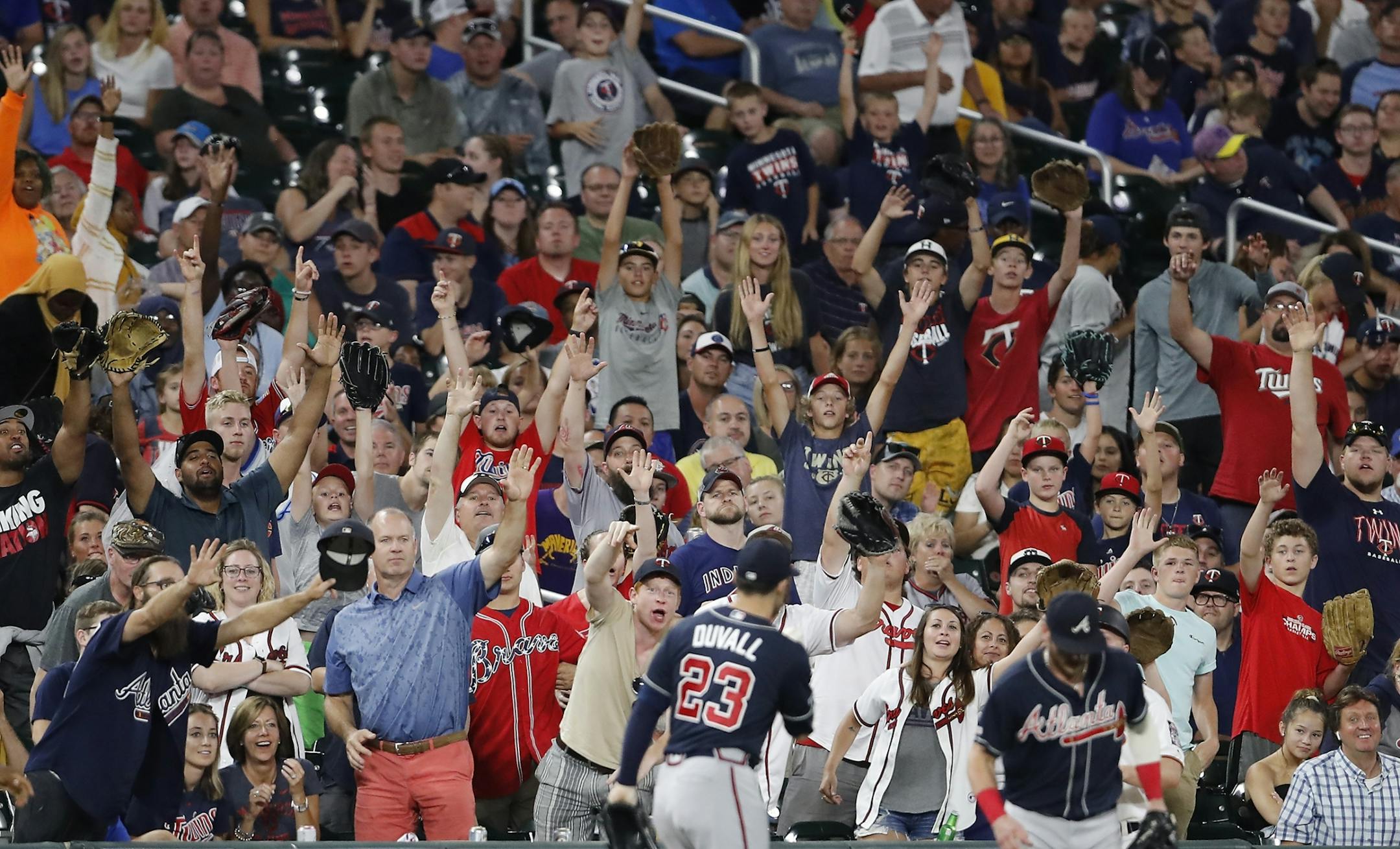 Fans yell for Atlanta Braves left fielder Adam Duvall (23) to throw them the fly ball he caught.