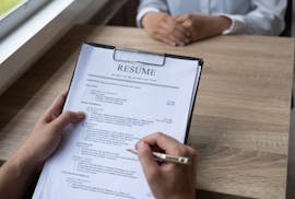 Employer interviewing a young male job seeker sitting at a table reading his CV resume viewed from above, Job interview concept.